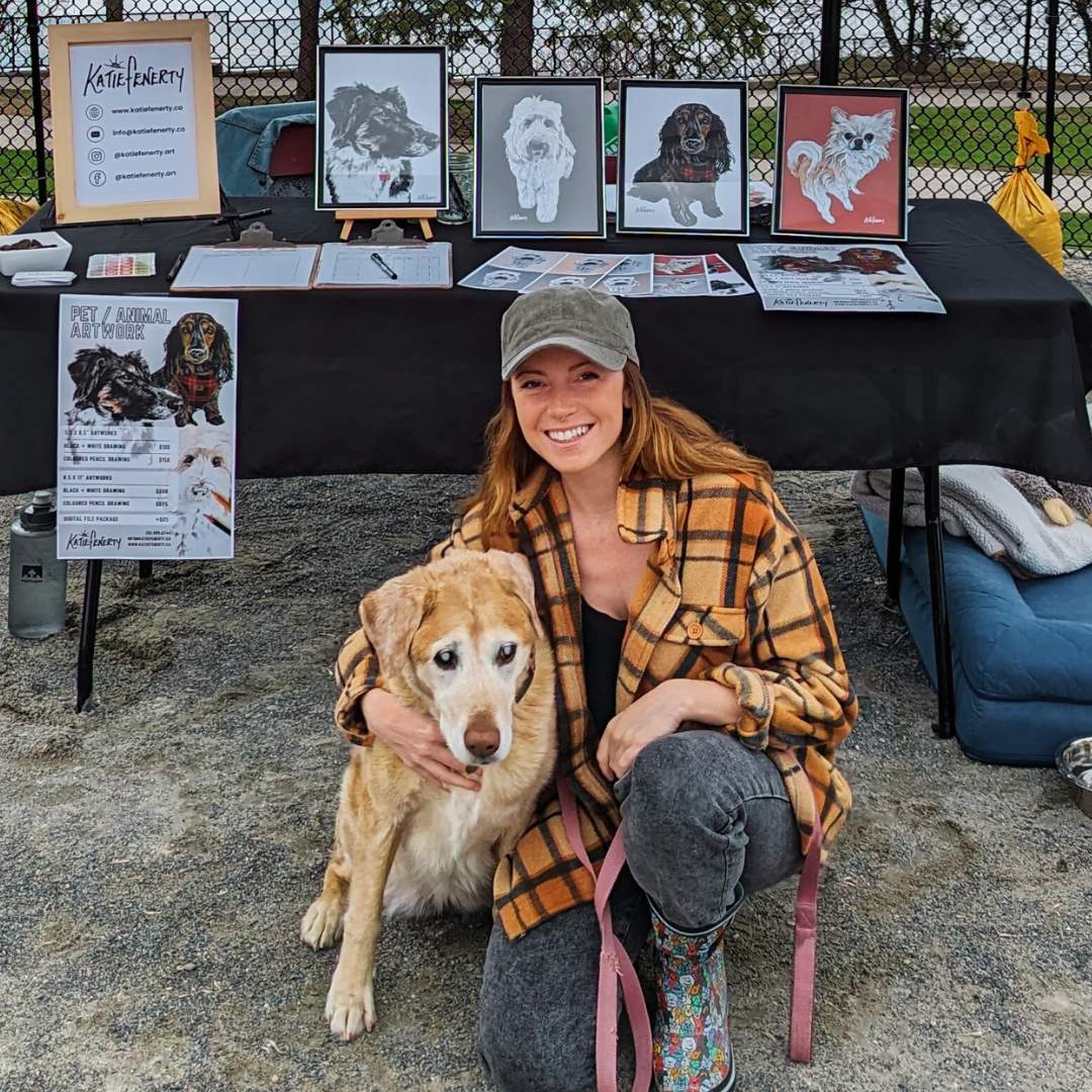 Katie fenerty at a market booth with her dog and artwork